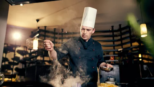 Ein Hotelkoch vor einem dampfenden Topf